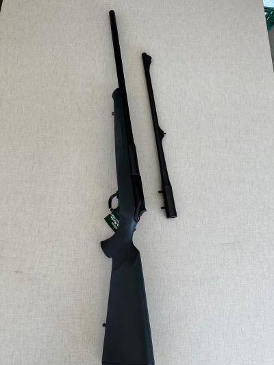 Arma de fogo de cano longo preto com cano adicional separado sobre superfície clara