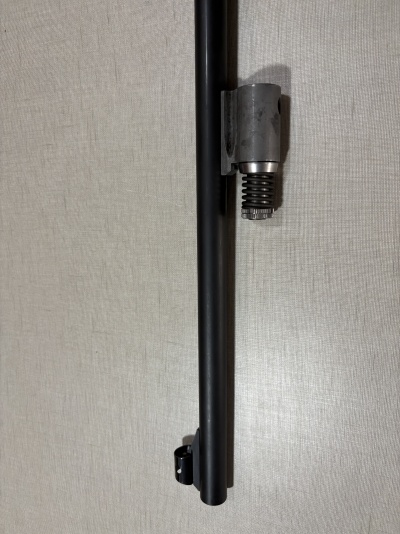 Tubulação preta com suporte de metal e mola em fundo cinza claro