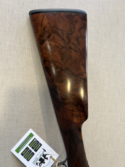 Parte da coronha de espingarda em madeira polida com etiqueta branca