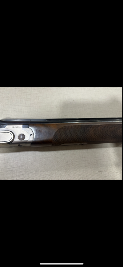 Espingarda de caça Beretta com coronha em madeira e metal sobre tecido claro
