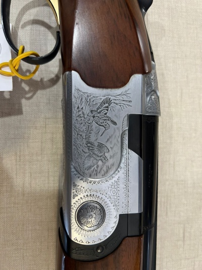 Espingarda de cano duplo com detalhes gravados em metal prateado e cabo de madeira