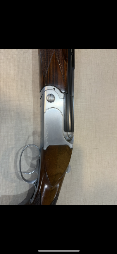 Espingarda clássica com coronha de madeira escura e metal prateado