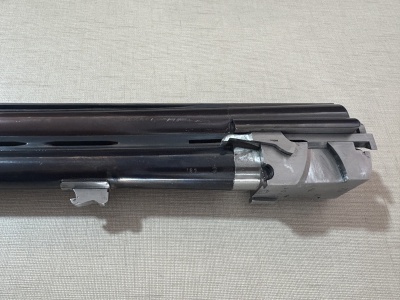 Parte superior e frontal de uma arma de fogo de canos paralelos em metal preto e cinzento