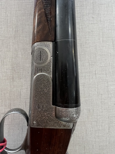 Espingarda de cano duplo com detalhes metálicos gravados e madeira escura