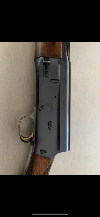 Espingarda com corpo metálico preto, gatilho dourado e madeira castanha polida