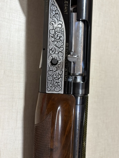Detalhe de uma arma de fogo com gravação floral e texto BENELLI ARMI