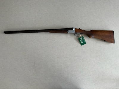 Espingarda de madeira e metal com etiqueta verde sobre superfície clara