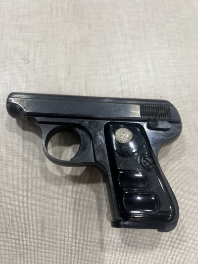 Pistola compacta preta com cabo sintético e símbolo metálico