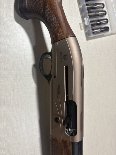 Espingarda com punho em madeira e corpo metálico cinzento com inscrições visíveis BERETTA e XPLOR ACTION.