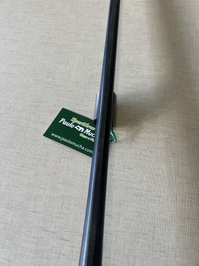 Vara de pesca preta sobre superfície bege com cartão verde ao lado