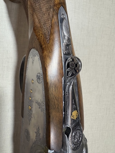 Close-up de uma espingarda com detalhes em madeira e metal gravado