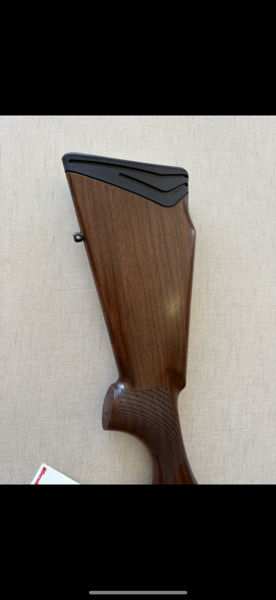 Coronha de arma de madeira castanha com acabamento em borracha preta.