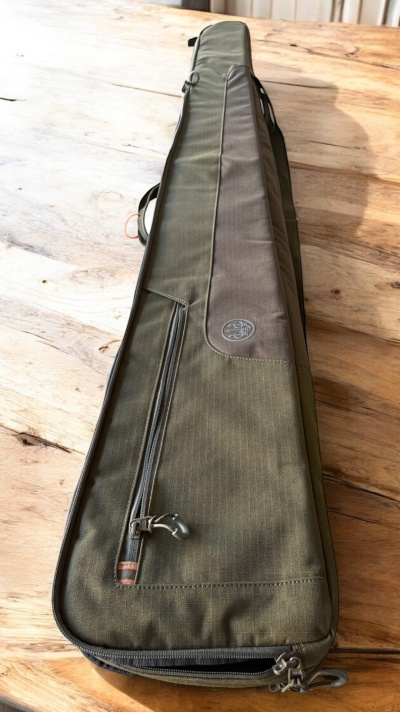 Capa verde escura para arma com bolso e alça sobre mesa de madeira