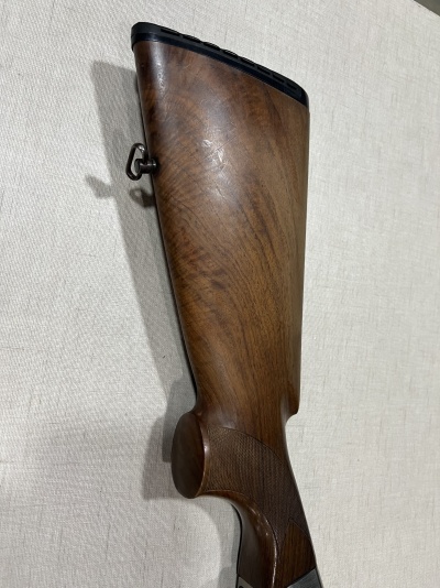 Coronha de espingarda em madeira castanha polida sobre tecido claro