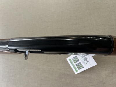 Espingarda com acabamento em metal preto e cabo de madeira sobre superfície cinzenta