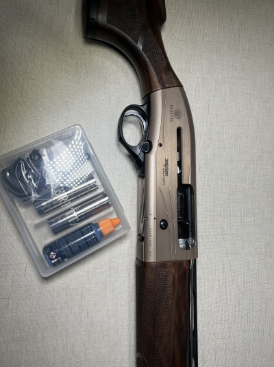 Espingarda Beretta A300 Outlander com acessórios em caixa transparente ao lado