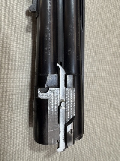 Parte de arma de fogo metálica preta e prateada com texto gravado
