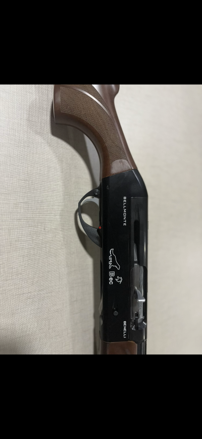 Espingarda com punho de madeira e corpo preto com inscrições e símbolos