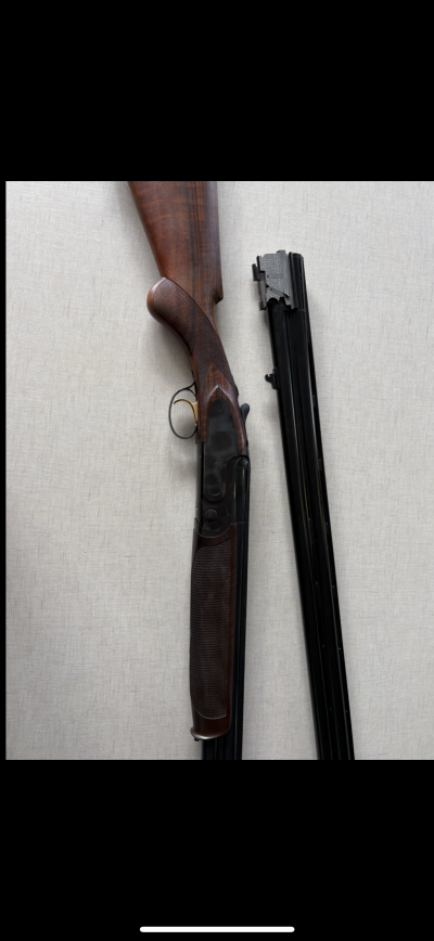 Espingarda de caça de madeira e metal em duas partes separadas em fundo cinzento.