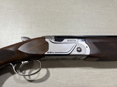 Espingarda Beretta 694 em metal e madeira sobre superfície cinza-clara