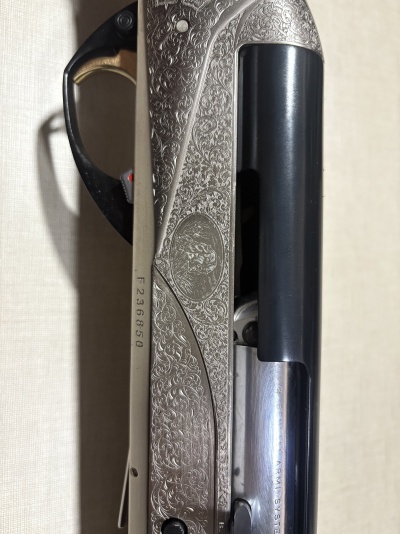 Espingarda com gravações ornamentais prateadas, detalhes pretos e número de série F236850