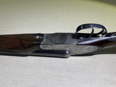 Espingarda de cano duplo com detalhes em madeira e metal gravado