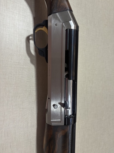 Parte de arma de fogo com punho em madeira, caixa metálica prateada e gatilho dourado