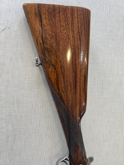 Coronha de arma de fogo em madeira polida castanha com textura natural e detalhes texturizados.