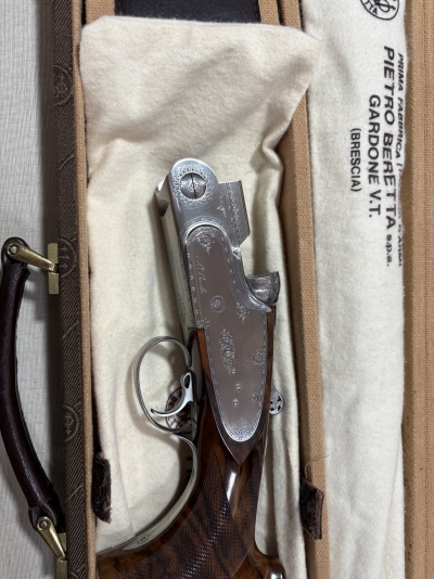 Espingarda de caça em estojo acolchoado branco com texto e estrutura em madeira e metal gravado