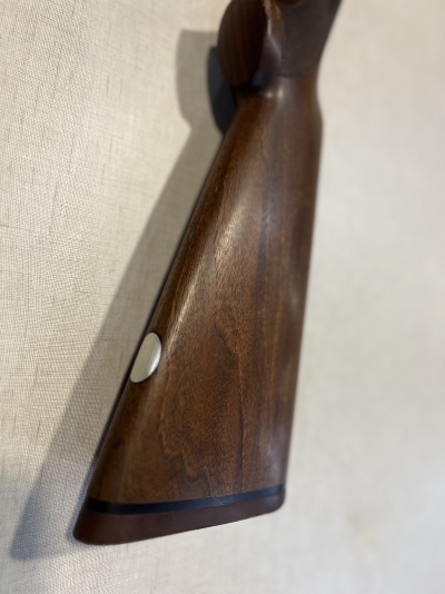 Coronha de madeira castanha lisa com botão metálico prateado em fundo branco