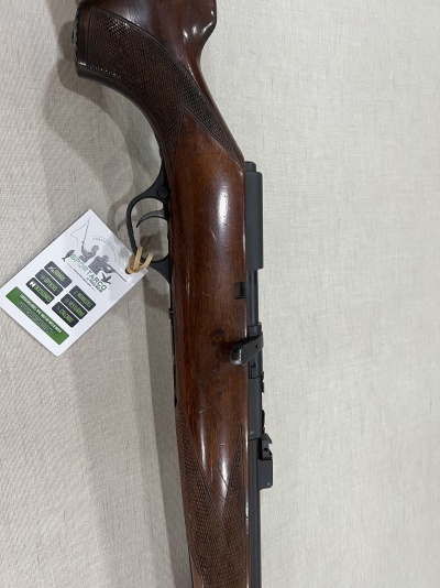 Carabina de madeira com etiqueta branca pendurada em fundo de tecido claro