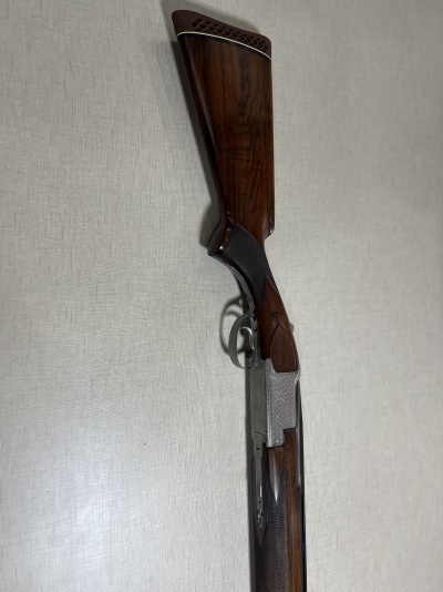 Espingarda de caça de madeira castanha com detalhes metálicos gravados