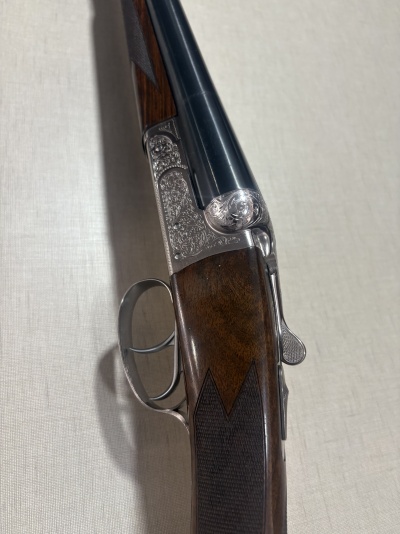 Espingarda de caça com coronha em madeira castanha e armação metálica prateada com gravações