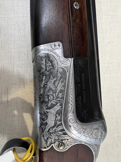 Espingarda com acabamento metálico gravado e coronha em madeira escura