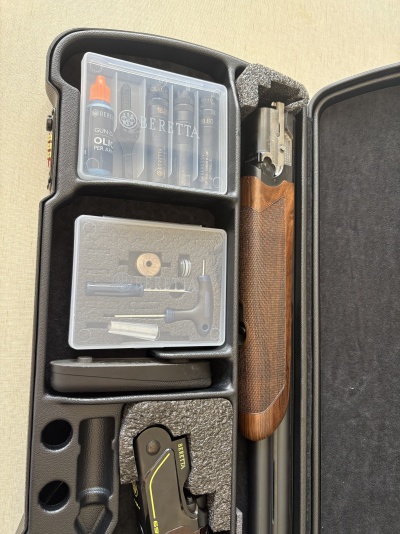 Arma Beretta com empunhadura de madeira e acessórios em mala preta com espuma.