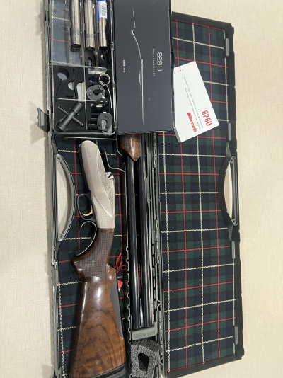 Estojo aberto com caçadeira desmontada, ferramentas e cartão '828U', fundo xadrez