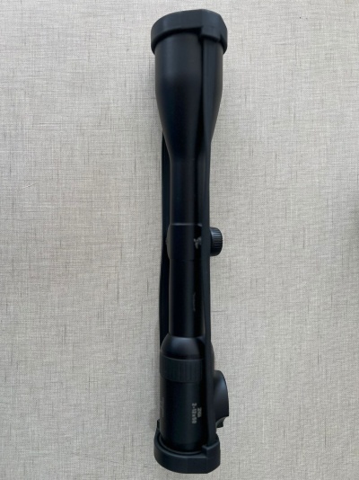 Mira telescópica preta sobre superfície cinza de tecido