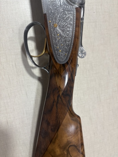 Carabina de madeira e metal gravada com padrão floral numa parede texturizada clara
