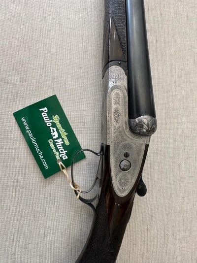 Espingarda de caça sobreposta com madeira e metal prateado gravado e etiqueta verde da marca