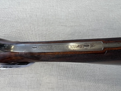 Espingarda com armação metálica e cabo em madeira escura com gravura texto