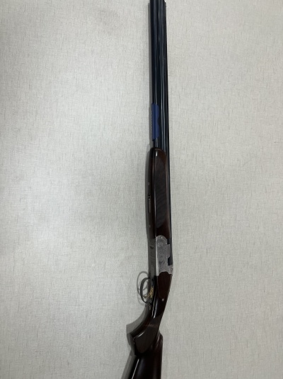 Espingarda de canos duplos em madeira e metal contra parede branca