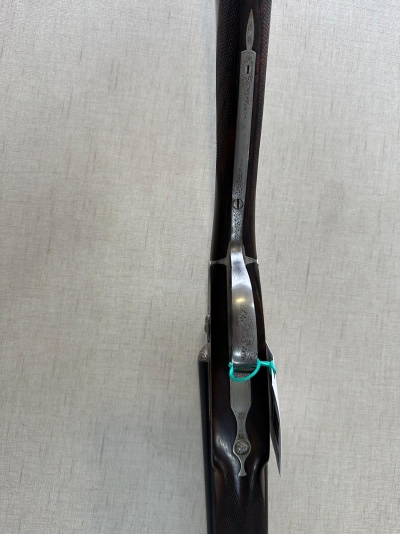 Rifle de cano duplo com madeira castanha e detalhes em metal prateado