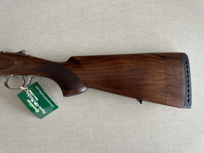 Espingarda com coronha de madeira escura e etiqueta verde pendurada