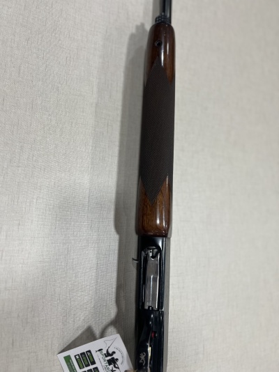 Espingarda com coronha em madeira e partes metálicas pretas sobre superfície clara