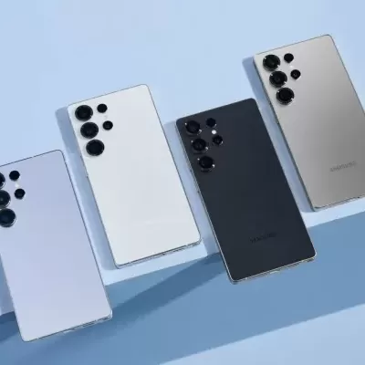 Quatro smartphones de diferentes cores com câmaras traseiras múltiplas sobre superfície azul