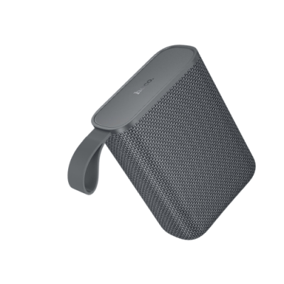 Coluna portátil Bluetooth cinzenta com textura de tecido e alça flexível para transporte.