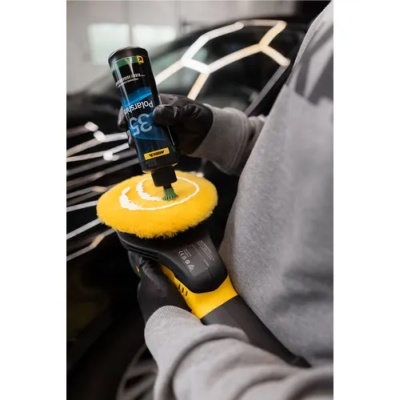 Pessoa aplicando produto numa polidora elétrica com esponja amarela.