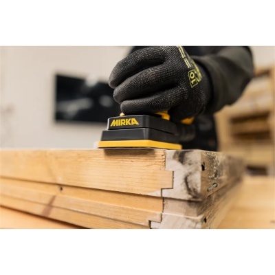 Lixadora manual Mirka a lixar madeira clara com mão enluvada preta