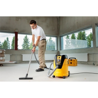 Aspirador industrial amarelo e preto MIRKA com homem a aspirar chão num espaço amplo