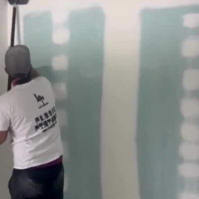 Profissional a lixar paredes e teto com ferramenta de longa pega em gesso cartonado